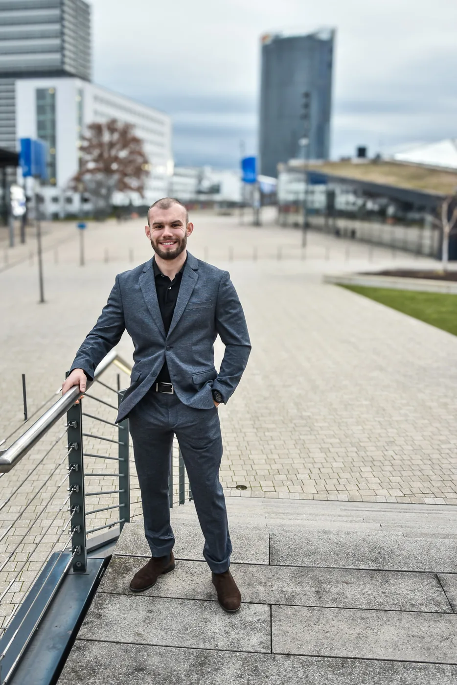 Businessporträt eines Mannes an einem Geländer vor urbaner Kulisse